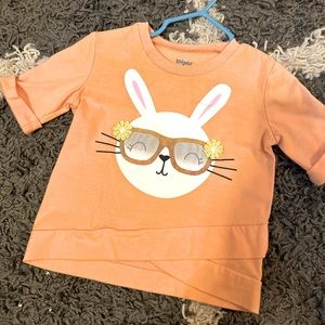 An Easter shirt that’s a lightish orange color from boutique 18 mos